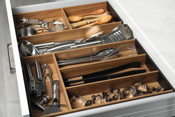 Different utensils in open desk drawer indoors