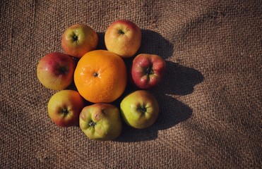 Orange Amid Apples with Water Droplets Isolated on Burlap Background, Perfect for Wallpaper