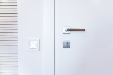 white closed door with a metal handle and hardware on a white wall background