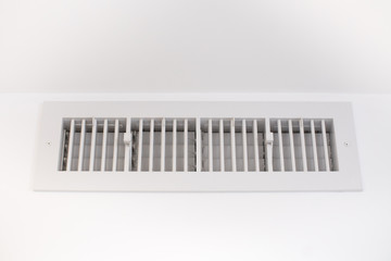 Ventilation grill filtering air on a white wall under the ceiling