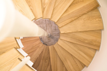 Spiral staircase with wooden steps on a metal base. View from top to bottom.