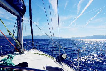 Summer travel concept: Blue sky and sea view from the front bow of a white sailing boat with copy space. White lines at sky. Colorful arming and ropes on boat