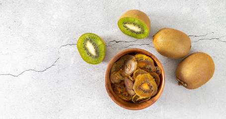Fototapeta na wymiar Homemade kiwi crunchy. Dried slices of kiwi chips on a light surface. Alternative healthy snack without sugar. Banner, top view, copy space