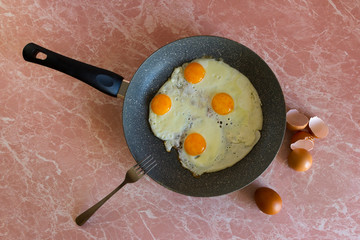 fried eggs in a pan, eggshell on a background table, closeup