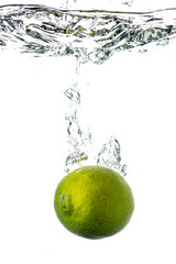 Fototapeta na wymiar whole and sliced green lime falling under water with a splash and bubbles on a white or black background