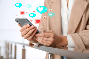 Young woman using smartphone indoors, closeup. Social media