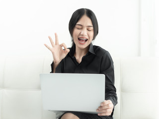 Asian woman in blank using laptop sitting on sofa at home, quarantine concept.