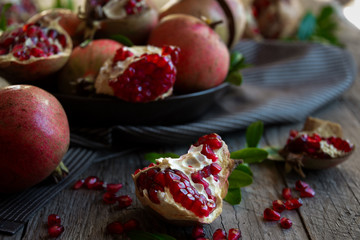 Fresh organic pomegranate fruit with leaves on dark background