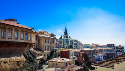 Fototapeta na wymiar Valparaiso, Chile - March 08, 2020: Far View to the Cathedral and Colored Buildings with Bright Painting on the Street