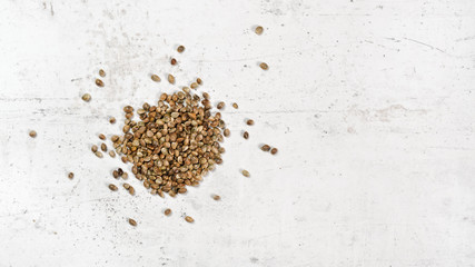 Cannabis seeds on white stone like board, view from above - space for text right side