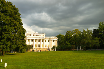 St. Petersburg. City park on Elagin Island. View of the beautiful Elaginskiy Palace from a green lawn called Oily Meadow. Silhouettes of tourists and townspeople on the stairs near the palace