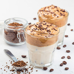 Trendy korean drink Dalgona coffee with ice, garnished with grated chocolate, light gray background, square