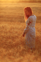 Fototapeta na wymiar girl at sunset in a wheat field sky
