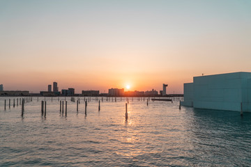 Fototapeta premium Abu Dhabi Cityscape SUNSET skyline, with buildings, river water and skyscrappers. Beautiful Emirates City at dusk. Orange sun.