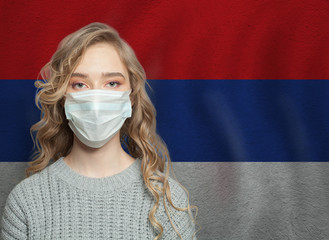 Young woman wearing a face mask with Serbia  flag. Flu epidemic and virus protection concept