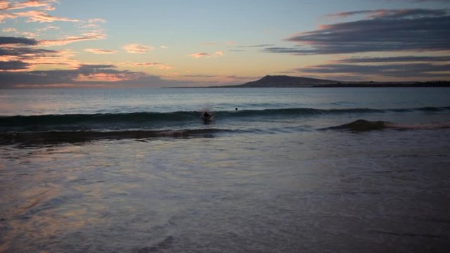 Early morning surfers catching some waves at sunrise.