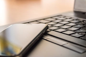 Close up of a cell phone and laptop keyboard, mobile phone and laptop, working at home - Image