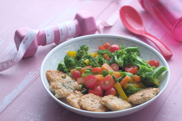 Fresh homemade salad in a plate with dumbbell on table 