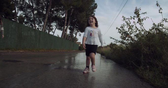 Cheerful little girl splashing in the puddles