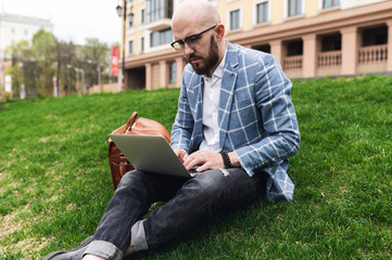 Young man using laptop outdoor. Freelance, student lifestyle, education, technology and online shopping concept