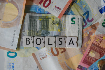 Stock market word placed above some euro bills as a symbol of the Spanish stock exchange