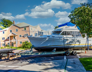 A large cabin cruiser being towed behind a truck on a trailer