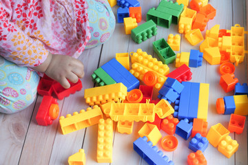 child girl paying with with building blocks on floor