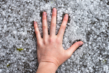 hand lies on the ground strewn with hail. A strong thunderstorm with hail