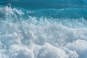 Fototapeta na wymiar Texture Light blue surface of raging sea water with white foam and wave pattern.The azure surface of the ocean. Waves break at the shore. Natural background.