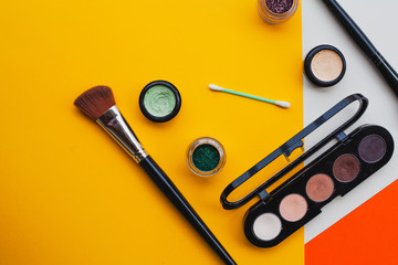 Creative flat lay of fashion bright nail polishes and decorative cosmetic on a yellow,orange and cream background. Minimal style. Copy space. Beauty blogger concept. Top view.