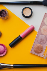 Creative flat lay of fashion bright nail polishes and decorative cosmetic on a yellow,orange and cream background. Minimal style. Copy space. Beauty blogger concept. Top view.