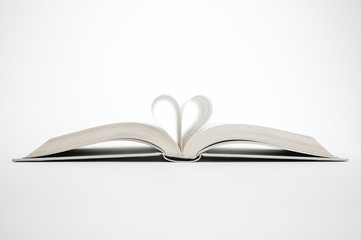 Libro abierto con páginas formando un corazón sobre fondo blando