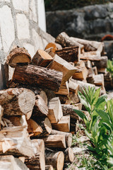 Wood folded in a row near a stone wall and grass