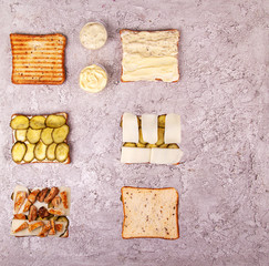 Step-by-step preparation sandwich with chicken meat, marinated cucumbers, mozzarella cheese and sauces over on grey concrete background. Geometric Layout Ingredients composition. Top view. Flat lay.