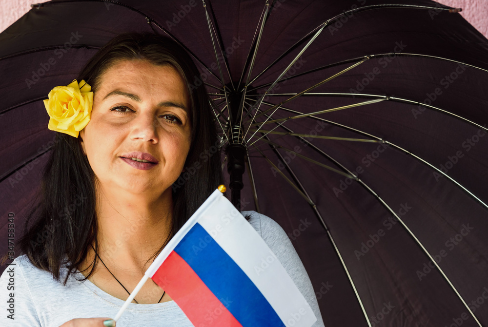 Wall mural  Woman with umbrella holds flag of Russia in front of isolated wall background