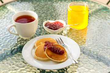 Pancakes with jam tea and juice on the table