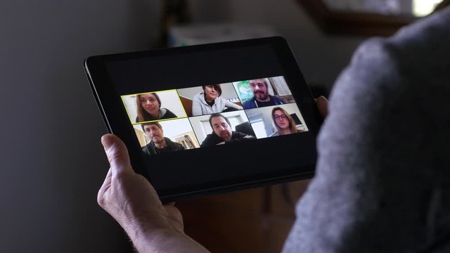 mature woman in video call on tablet with her son's friends