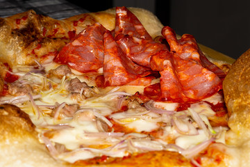 closeup of soft pizza topped with tomato mozzarella salami sausage onion