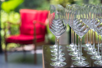 Empty wine glasses arranged in row over red chair in blurry backgroud