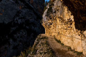 A close-up shot of the hiking trail on the side of a cliff in the natural park of Congost de Mont-rebei illuminated by sunlight (Spain)