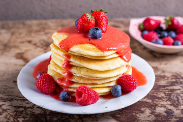Stack of homemade pancakes with syrup and berries. Typical American breakfast or snack.