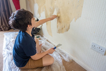 A child stripping wallpaper as the first step in redecorating.