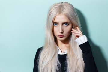 Studio portrait of young blonde girl with blue eyes on background of aqua menthe color.