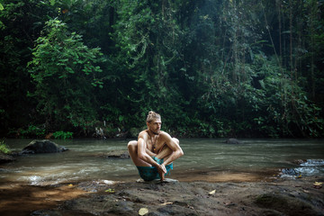 Yoga practice and meditation in nature. Man practicing near river