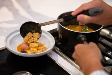 chef pouring chicken to curry bowl