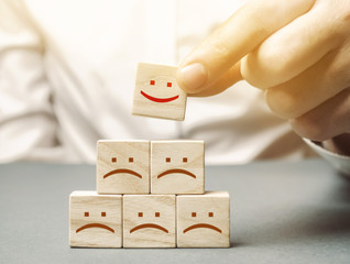 One block with a positive face stands out from the rest of the negative emotions. Concept of good...