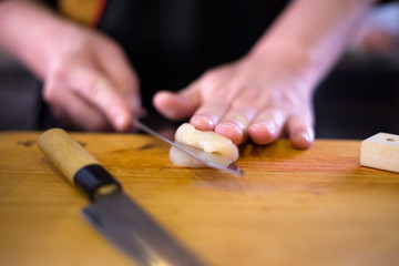 Japanese chef is neatly cutting on hotate