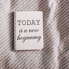 Today is a new beginning motivational quote wrote on a paper in notebook.