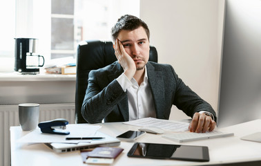 An overworked employee works on a desktop computer. Tired businessman or office worker falls asleep at the workplace. Sales manager, financial analyst or IT specialist, freelancer.