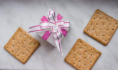 Flat lay. Top view. New Year's gift with bow of pink ribbons and lean ruddy crackers with bran on white background